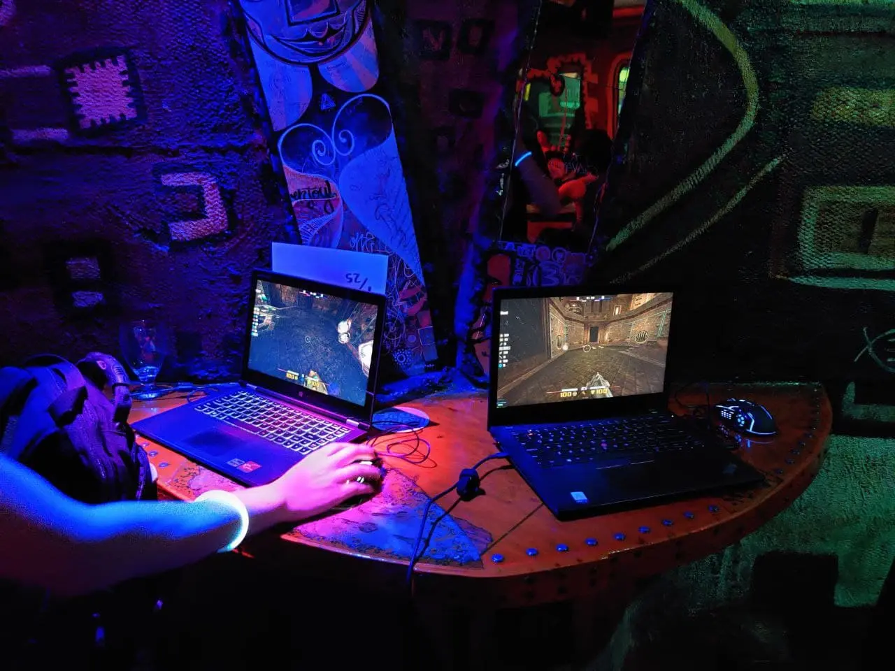 Two laptops running Quake in an ultraviolet themed night club.